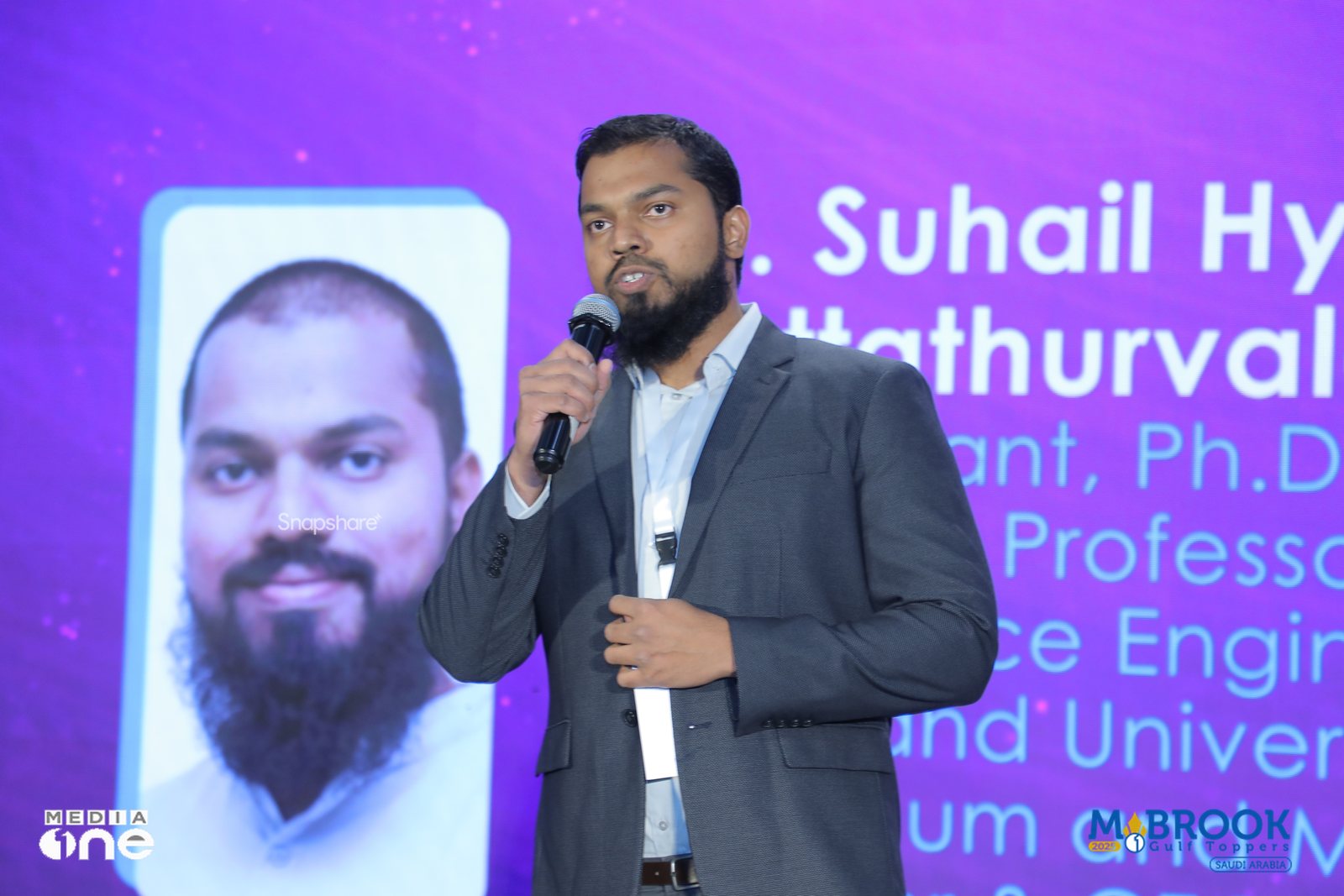 Dr. Suhail Hyder Vattathurvalappil presenting on stage at the Mabrook Gulf Toppers event in Saudi Arabia